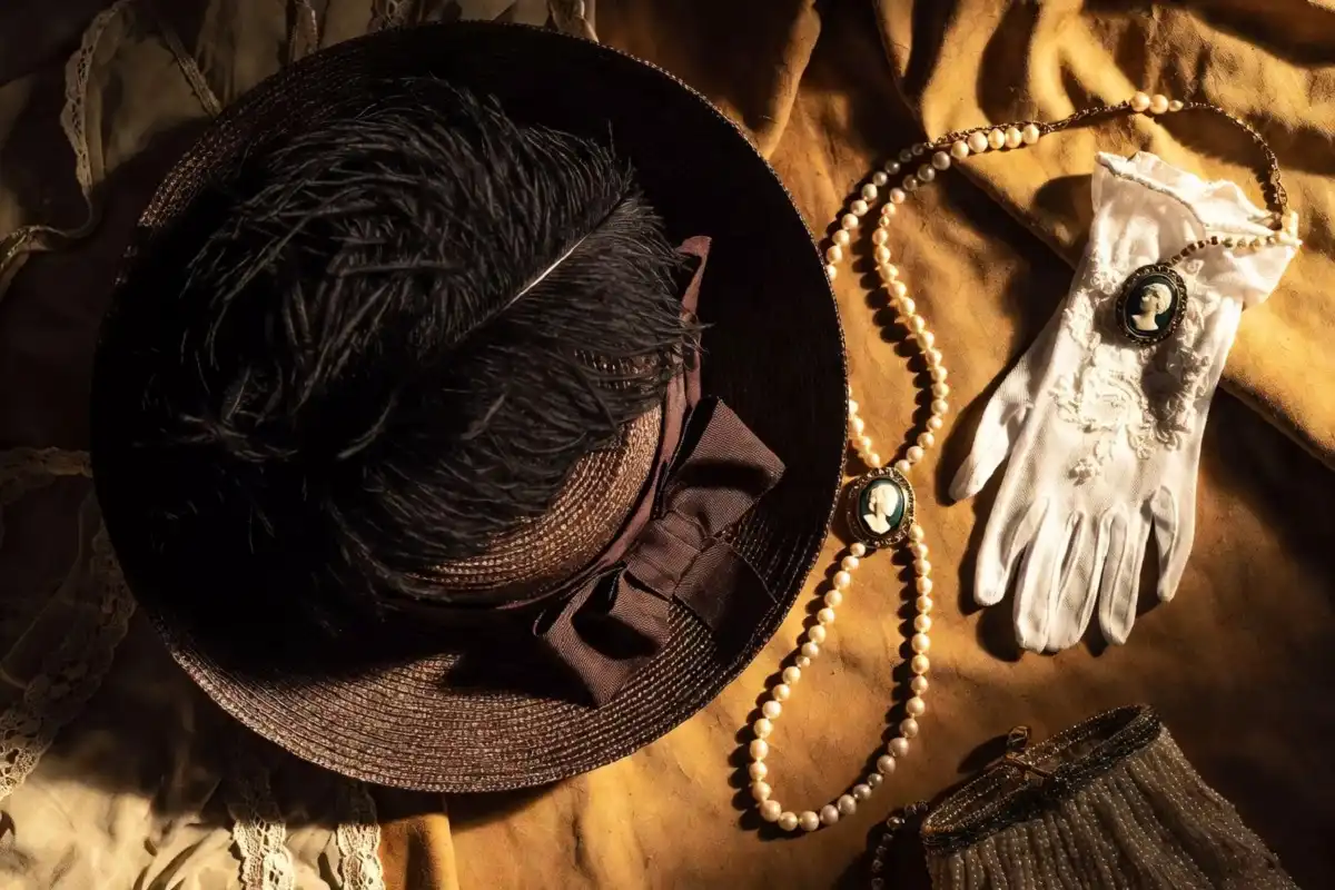 Close-up of 1900s Edwardian fashion accessories including feathered hats, lace gloves, and pearl jewelry
