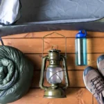 Flat lay of essential gear from a beginner camping checklist including tent and sleeping bag