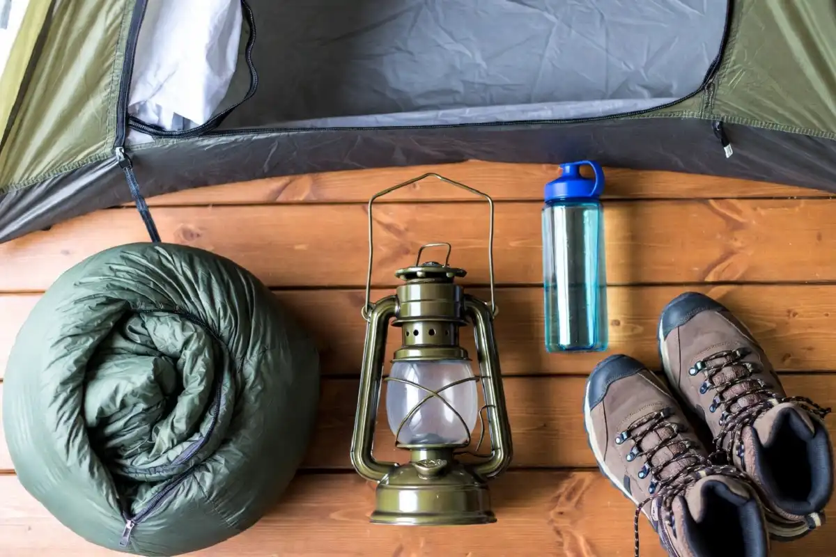 Flat lay of essential gear from a beginner camping checklist including tent and sleeping bag
