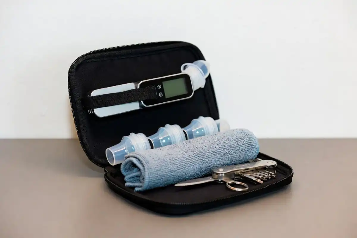 Compact travel gadgets such as a luggage scale, silicone bottles, and a microfiber towel in an open pouch