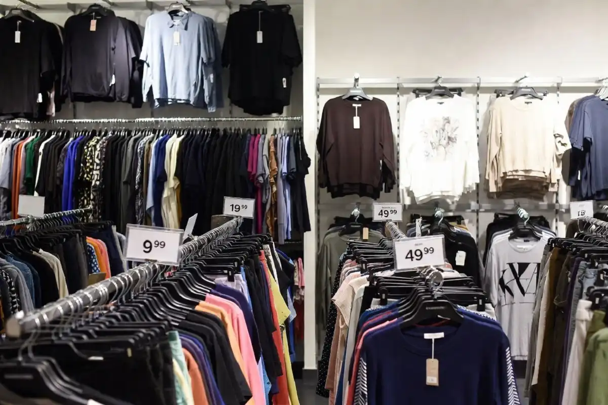 Fashion brand comparison layout showing clothing racks with price tags and quality labels