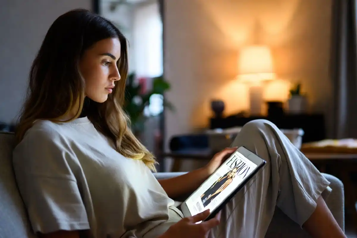 Woman reading a digital fashion magazine subscription on a tablet at home