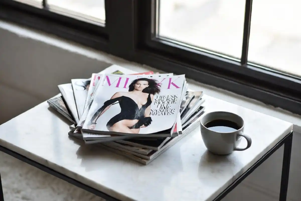 A neat stack of fashion magazines subscriptions on a marble table with coffee