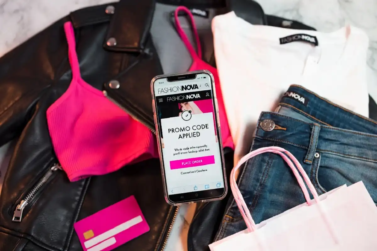 Fashion Nova discount codes displayed on a smartphone screen next to stylish clothing and shopping bags