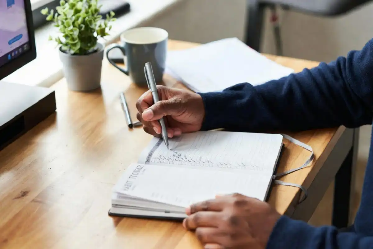 Person tracking habit progress in a notebook to stay consistent