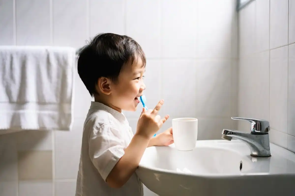 Child brushing teeth and washing hands as part of a daily hygiene routine
