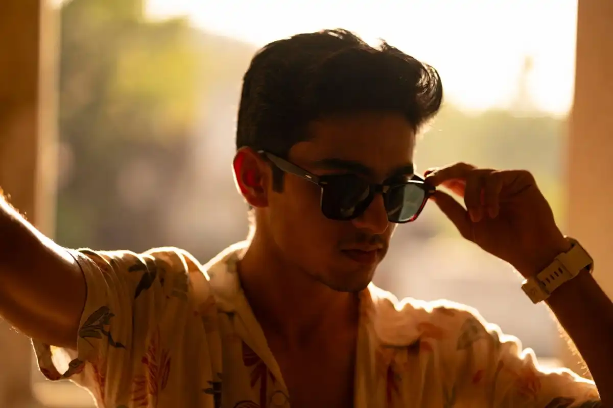 Man accessorizing a summer outfit with sunglasses and a watch