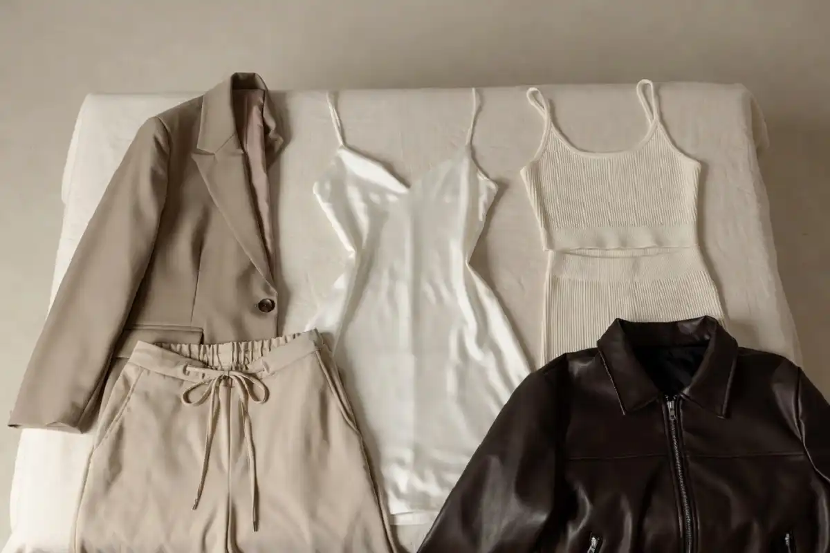 fashion capsule wardrobe laid out flat with neutral co-ords, slip dress, blazer, and wide-leg trousers