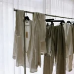 NAKD fashion outfits displayed on a minimal Scandinavian-style clothing rack with neutral tones and sustainable fabric tags