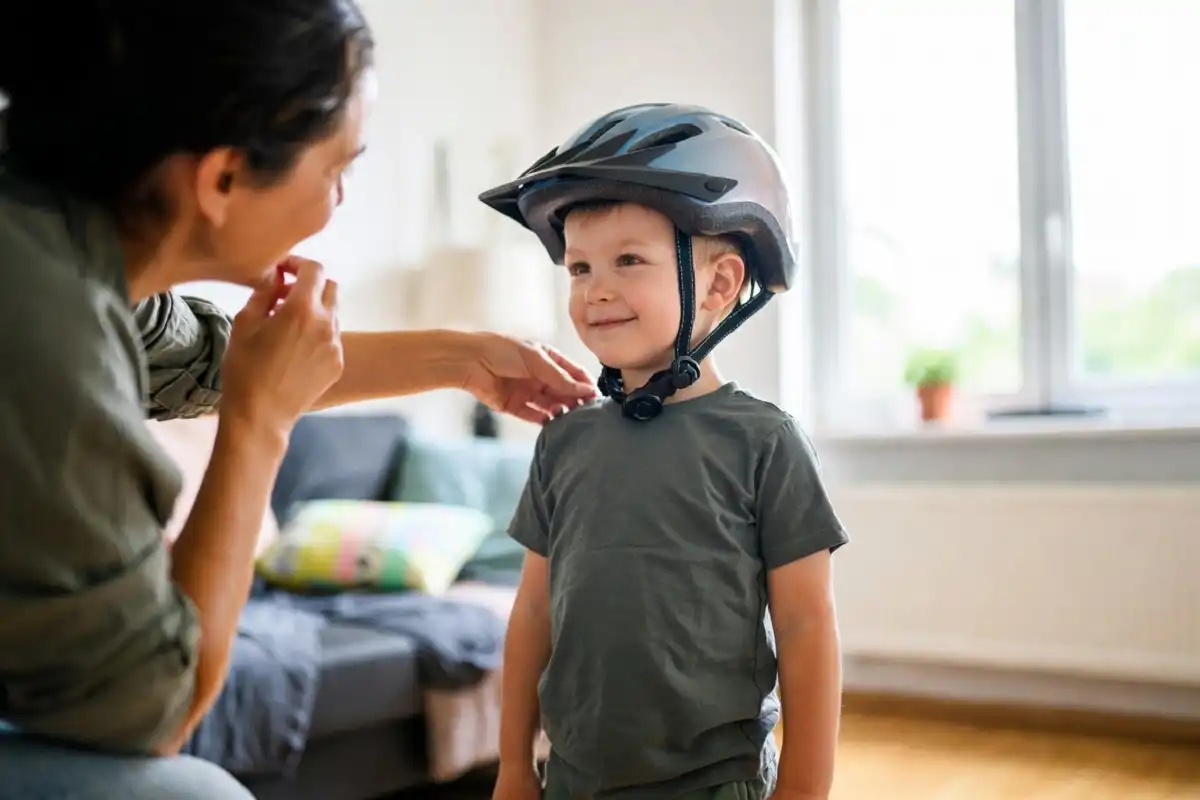 Parent adjusting a bicycle helmet to fit a smiling child correctly at home