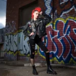 Young woman wearing punk fashion leather jacket with studs and patches on urban street