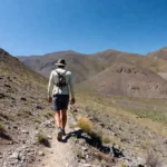 Hiker on a mountain trail using budget hiking essentials